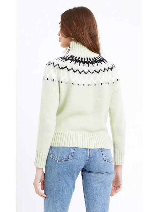 Back view of a woman wearing a soft pastel green turtleneck and an eye-catching abstract black and white design extending from the collar
