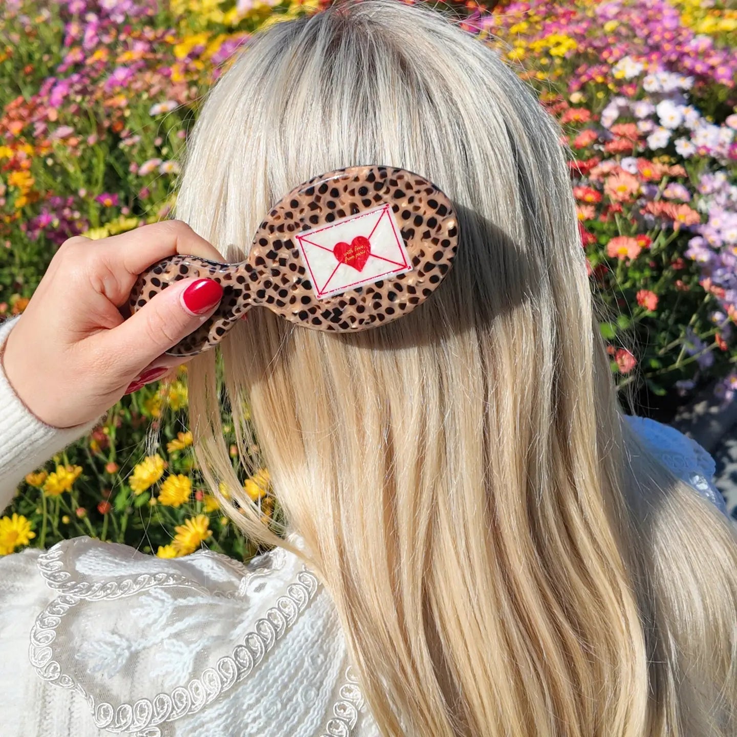 Person with a leopard print hairbrush with a heart design against a floral background
