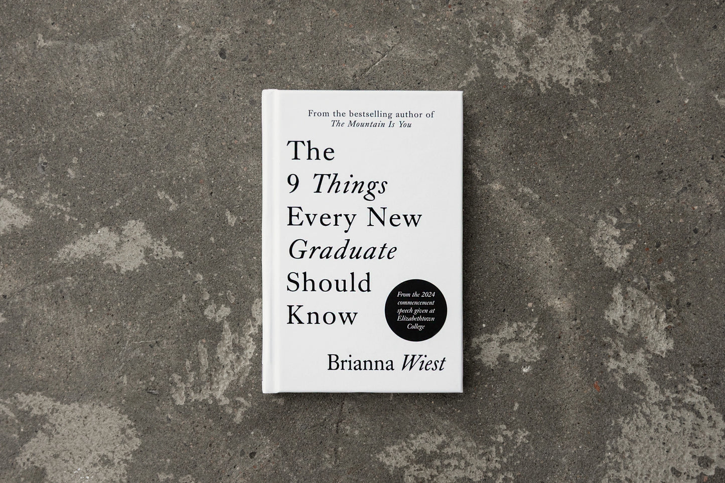 Book titled 'The 9 Things Every New Graduate Should Know' by Brianna Wiest on a textured surface