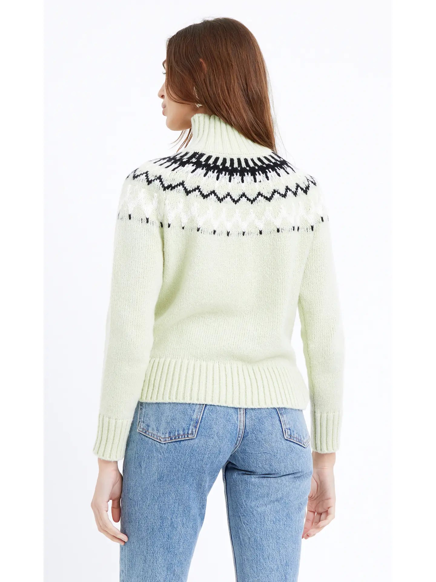Back view of a woman wearing a soft pastel green turtleneck and an eye-catching abstract black and white design extending from the collar