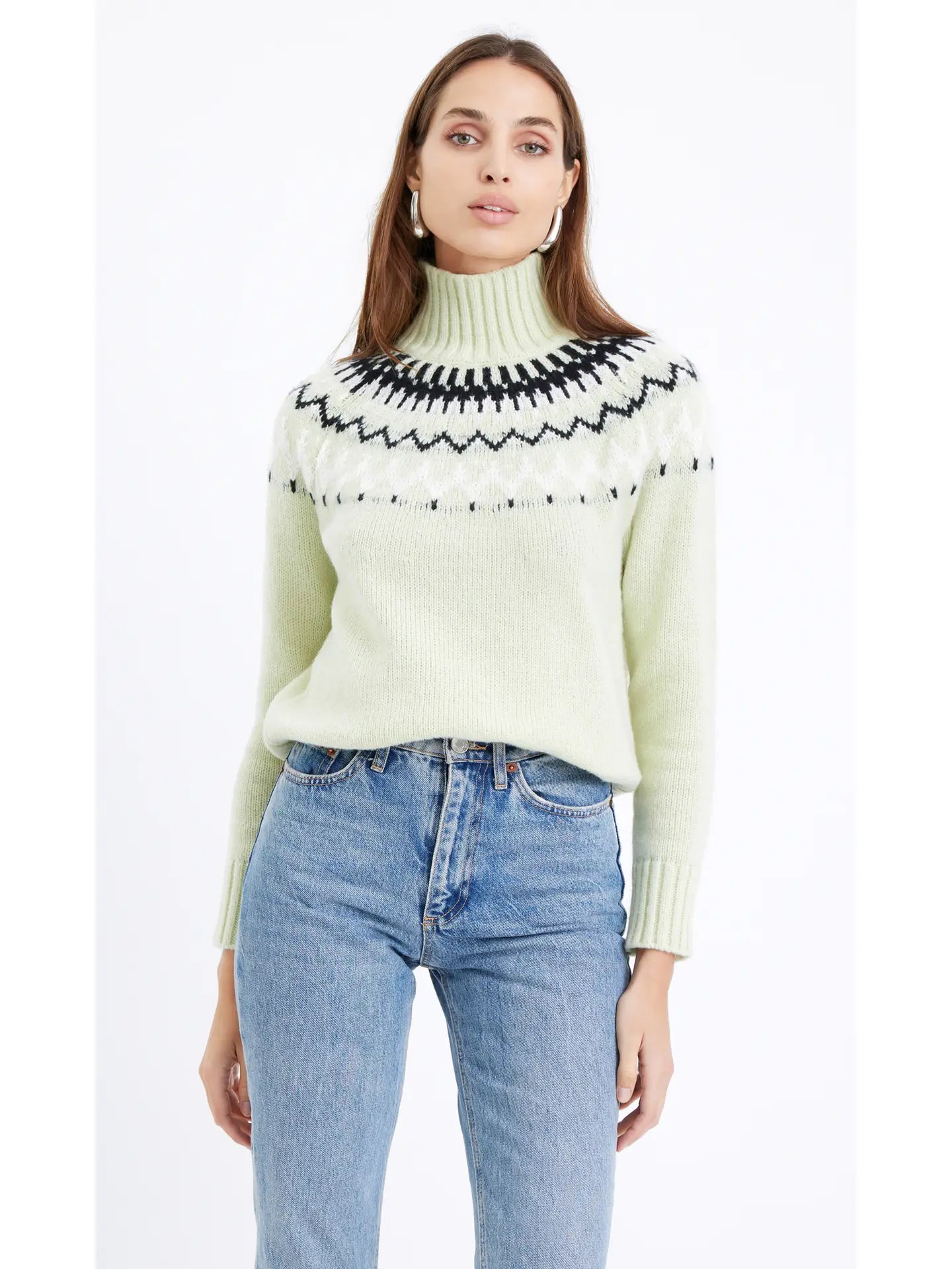 A woman wearing a soft pastel green turtleneck and an eye-catching abstract black and white design extending from the collar