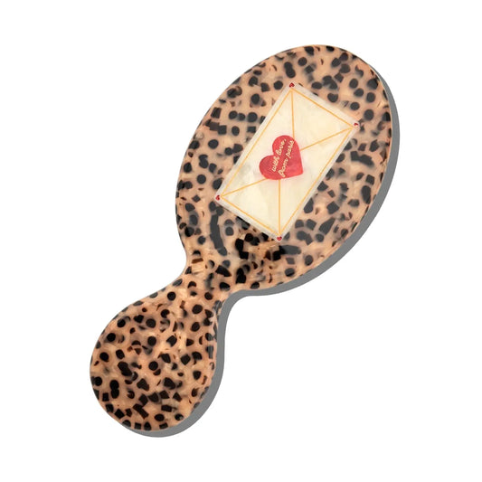 Leopard print purse-sized hairbrush with a red heart design on a white background