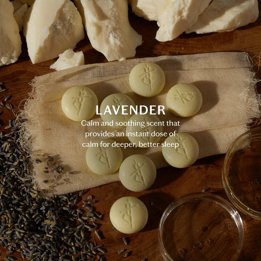 Lavender-scented bath pebbles on a wooden surface with lavender flowers and a jar, labeled 'Calm and soothing scent that provides an instant dose of calm for deeper, better sleep'.