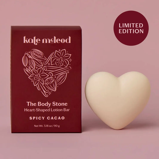 Heart-shaped lotion bar with packaging labeled Spicy Cacao on a pink background