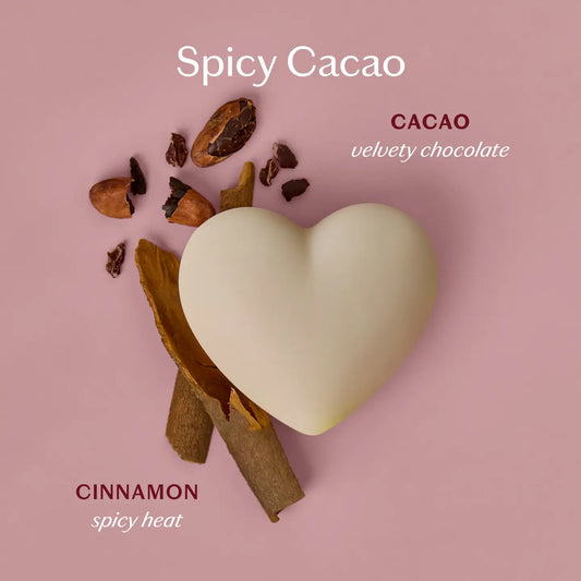 Heart-shaped cacao lotion body bar with cinnamon sticks on a pink background, labeled 'Spicy Cacao'.