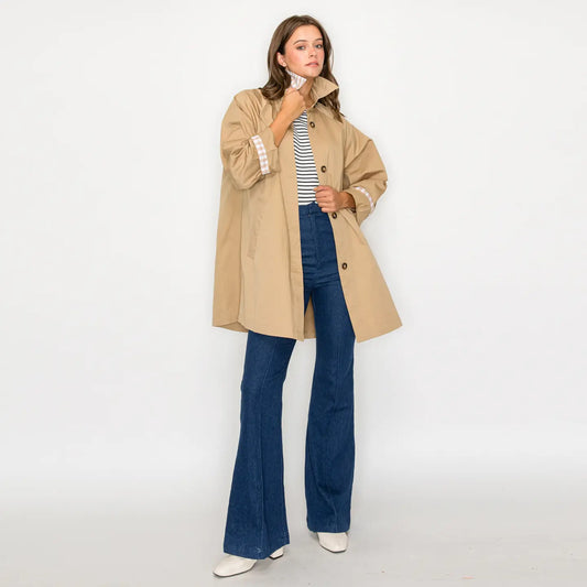 Woman wearing a beige mid-length trench coat on a white background