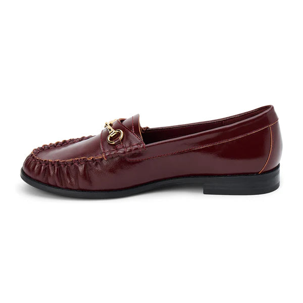 Burgundy leather loafer with gold chain detail on a white background
