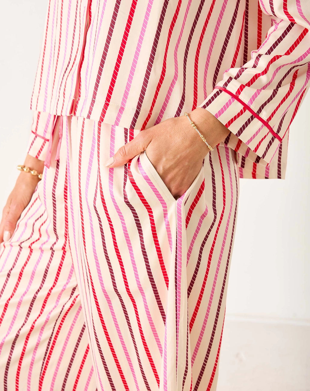 Person wearing a long, striped pjs with red and pink horizontal lines on a white background