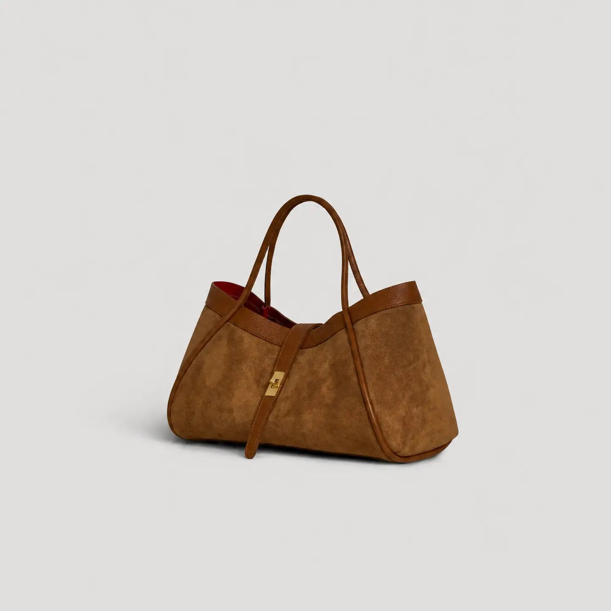 A brown suede tote bag with brown leather handles and trim, featuring a small gold-tone lock on a strap, set against a light gray background.