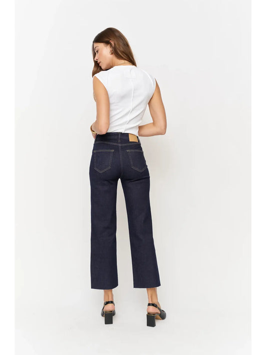 Back view of woman wearing high-rise denim wide leg crop, fitted through the hip, zipper fly, and a cropped raw hem.