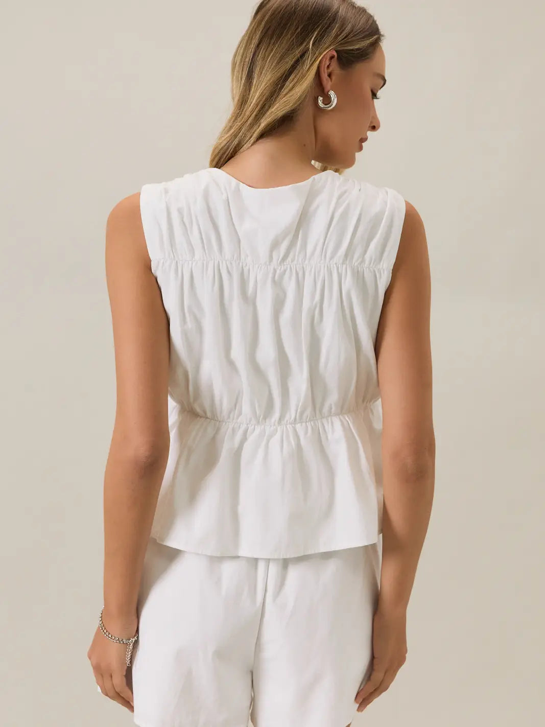 Back view of a woman wearing a front tie cinched linen white sleeveless top 
