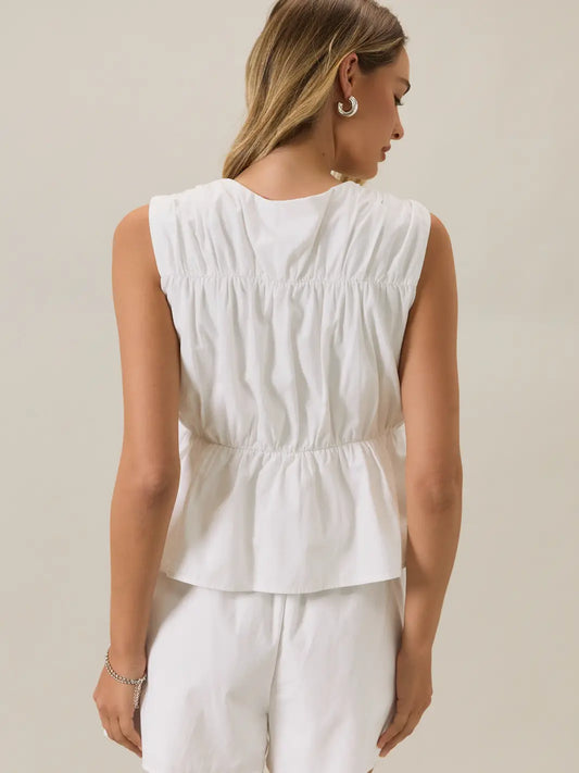 Back view of a woman wearing a front tie cinched linen white sleeveless top 
