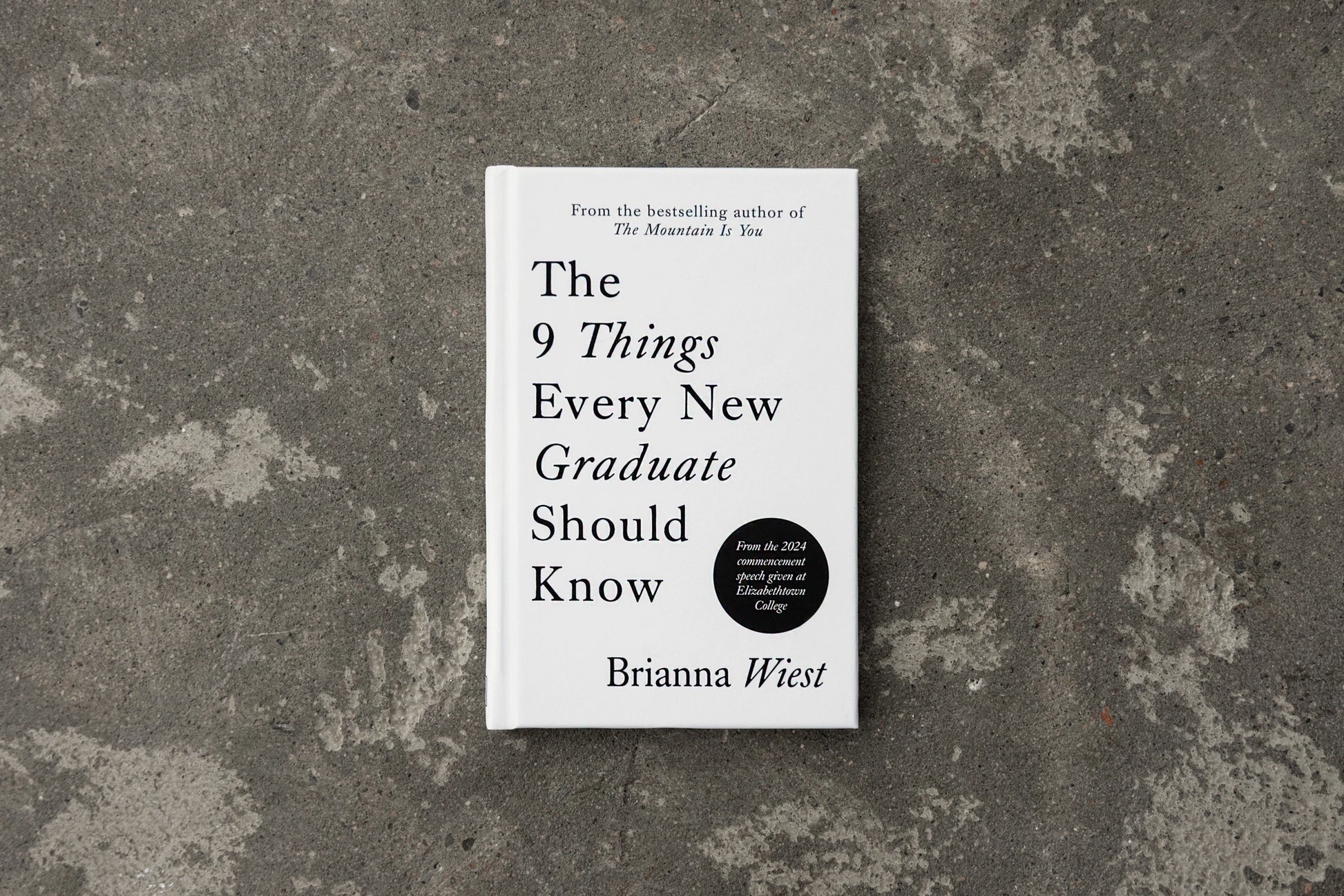 Book titled 'The 9 Things Every New Graduate Should Know' by Brianna Wiest on a textured surface