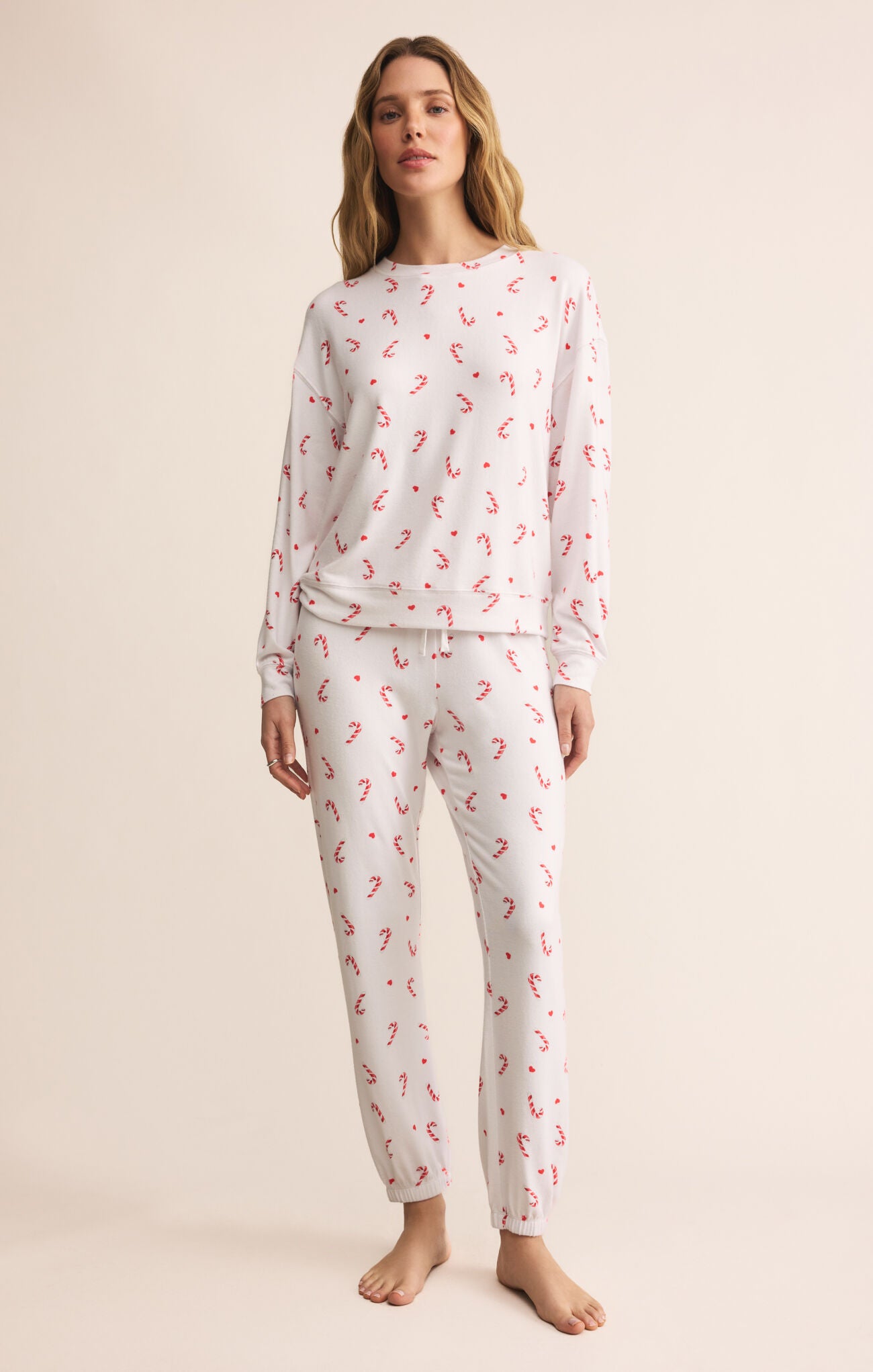 Woman wearing a white pajama set with red candycanes 