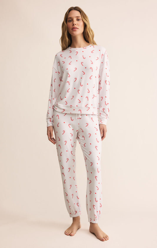 Woman wearing a white pajama set with red candycanes 