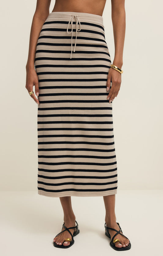 Person wearing a black and beige striped skirt on a plain background