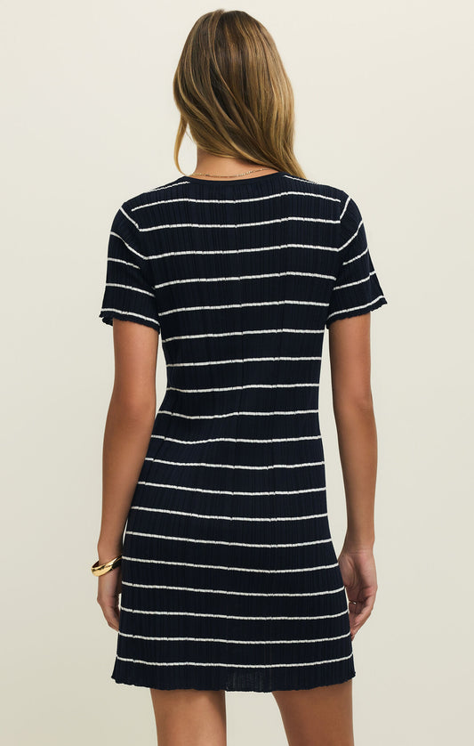 Back view of a woman wearing a navy and white striped mini dress against a plain background