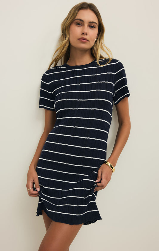 Woman wearing a navy and white striped mini dress against a plain background