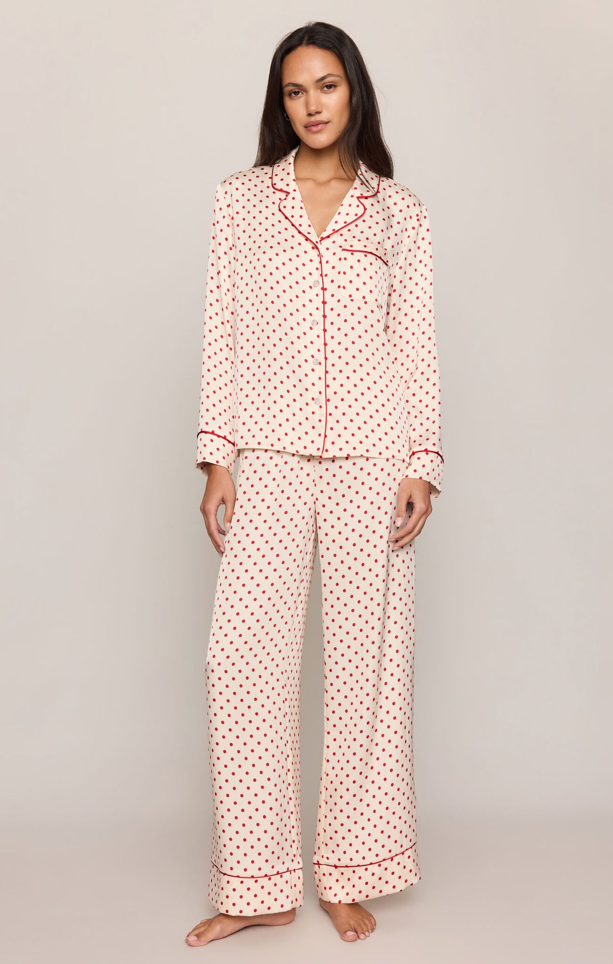 Woman wearing a pink polka dot pajama set on a plain background